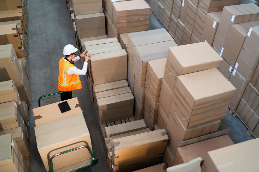 Logistic warehouse worker delivering boxes on a trolley